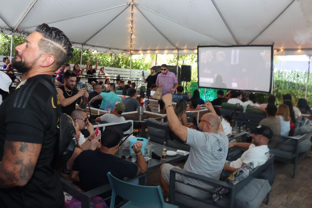 The Yard tented patio with giant projector screen and happy hour crowd at Grails Miami in Wynwood