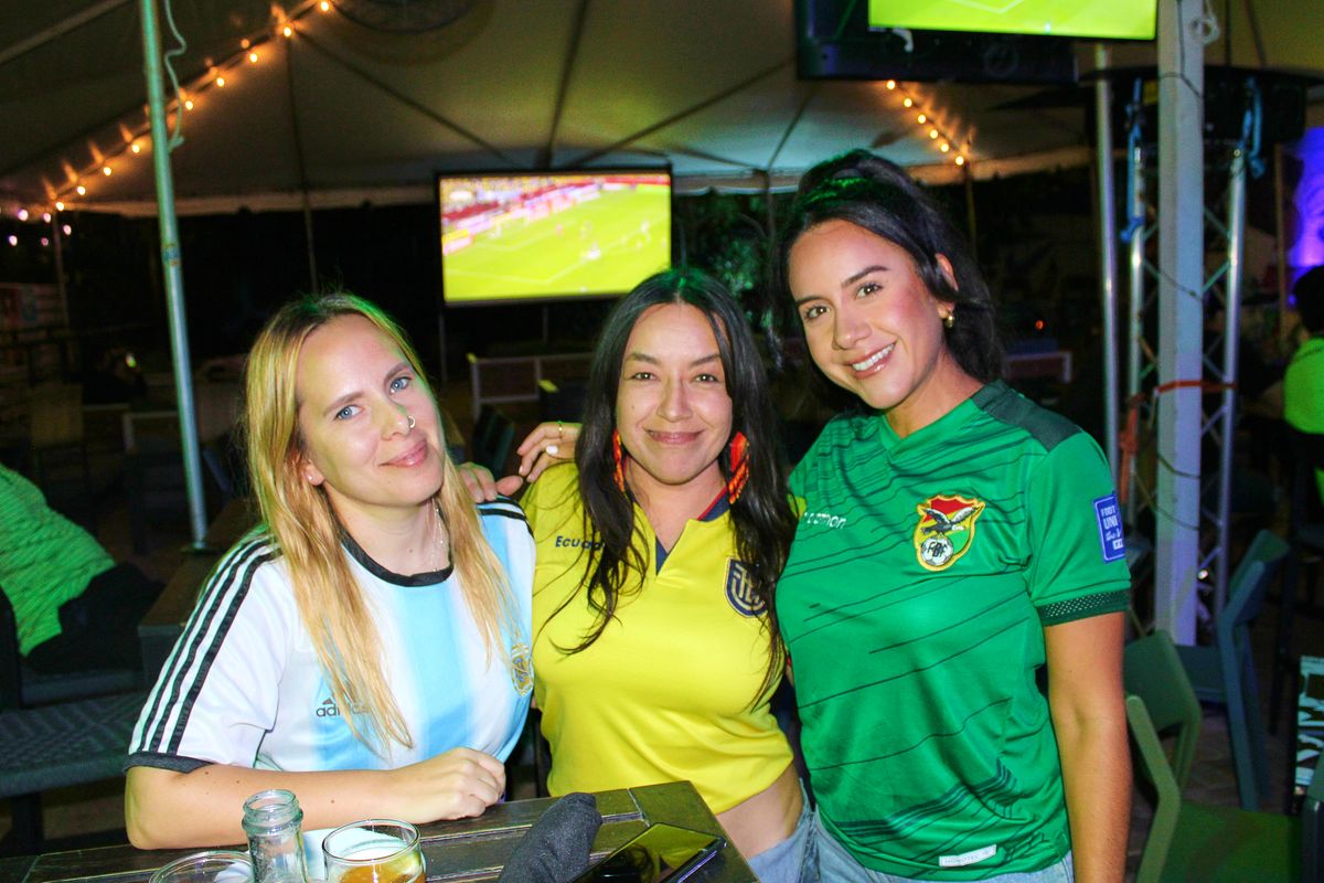 Three South American soccer fans in Argentina, Ecuador, and Bolivia national jerseys posing together on the Grails Miami patio for a Copa Libertadores watch party