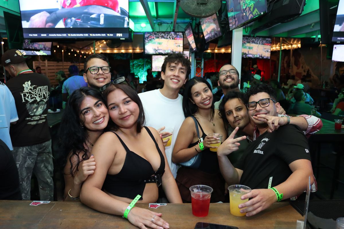 Seven friends posing with cocktails at Grails Miami bar