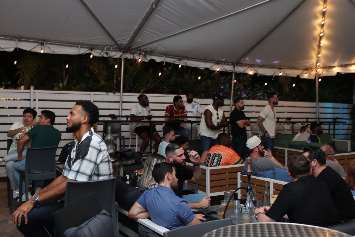 Crowd of soccer fans watching a Concacaf Gold Cup match on the covered Grails Miami patio in Miami