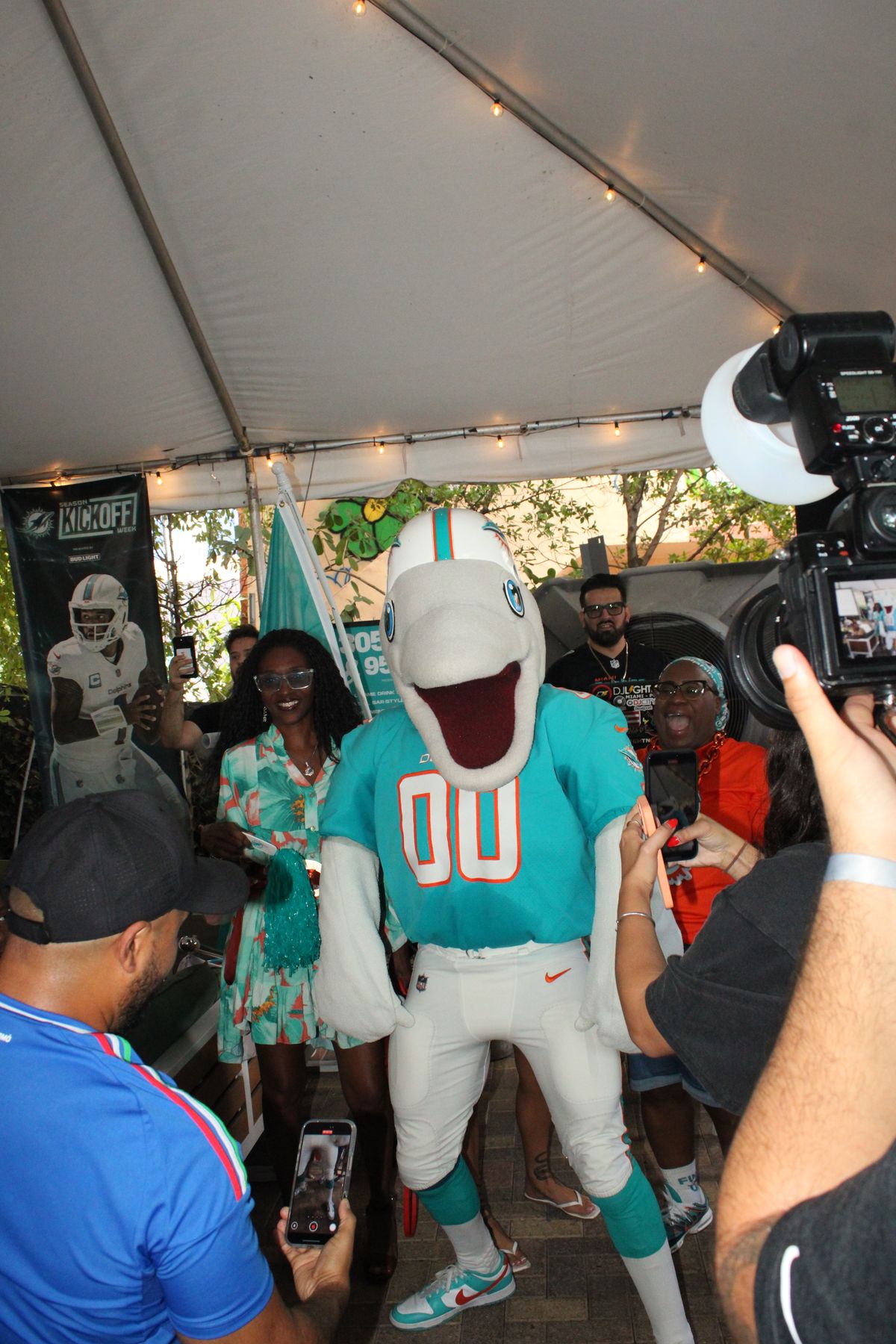 Miami Dolphins mascot T.D. posing with fans under the tent at the Grails Miami patio during a Miami Dolphins season kickoff party