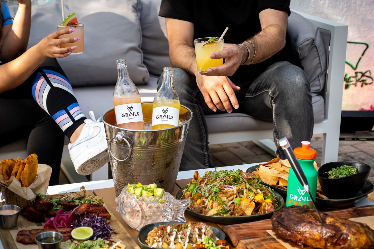 Shareable food and drink spread on a covered patio table at Grails Miami weekend brunch.