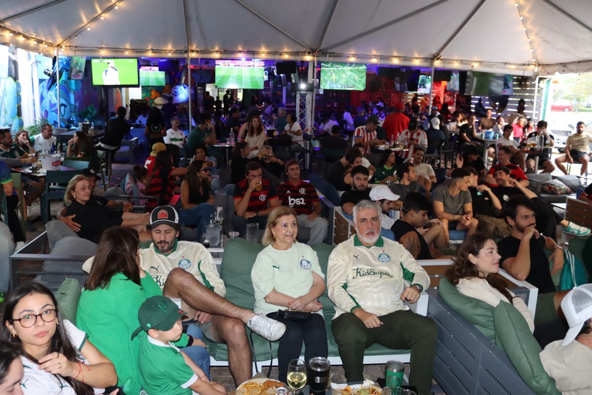 Family of Palmeiras fans in white-and-green jerseys seated on the Grails Miami patio during a Copa Libertadores Brasileiro derby