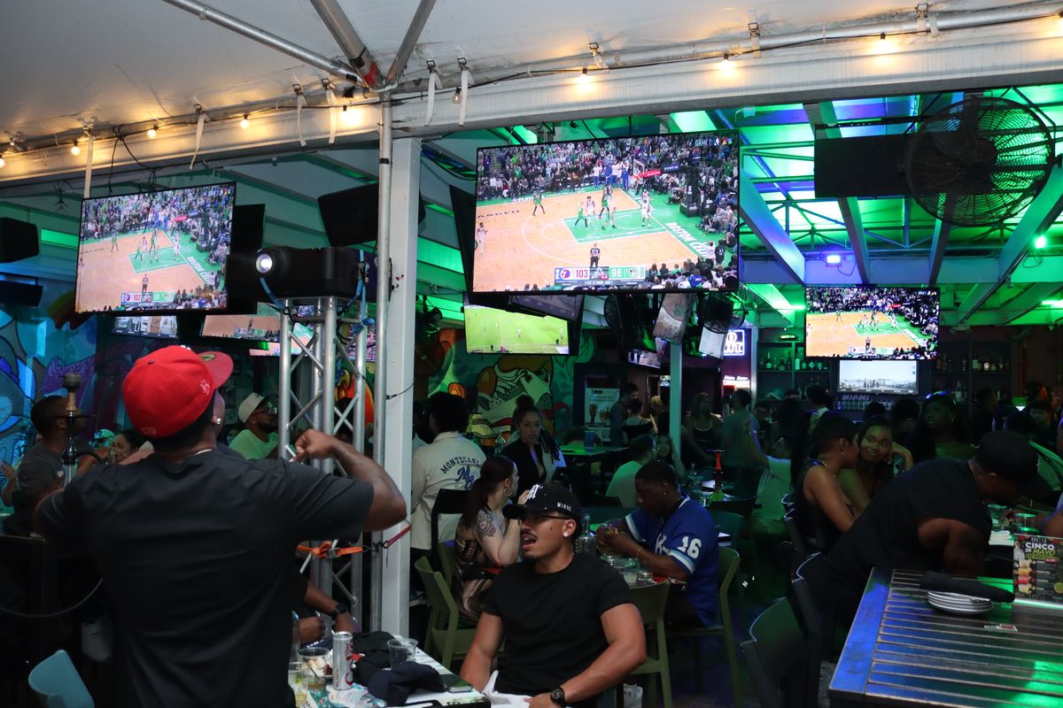 Crowded Grails Miami patio of fans watching an NBA Playoffs Game 7 on multiple overhead TVs