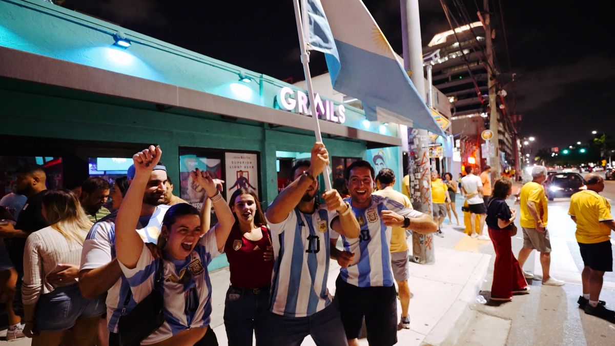 Group of Argentina soccer fans celebrating outside the Grails Miami entrance with a large Argentine national flag after a Copa Libertadores watch party