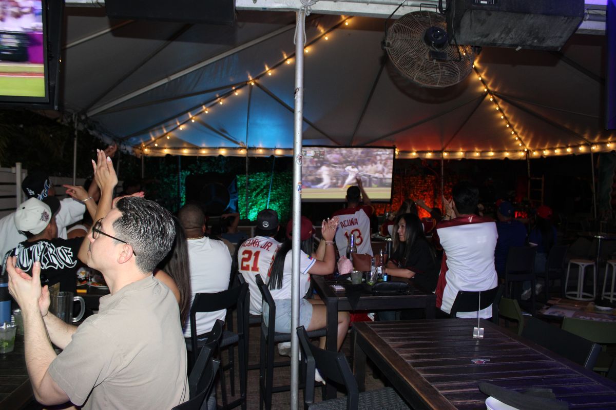 Venezuela Acuña jersey fans cheering as a play happens on the patio TV at Grails Miami during a Miami Marlins watch party
