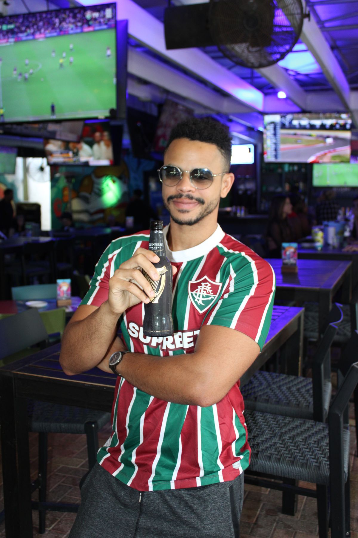 Single soccer fan in a club jersey with a Guinness while watching a UEFA Europa League match on the big screens at Grails Miami, Miami's home Europa League pub