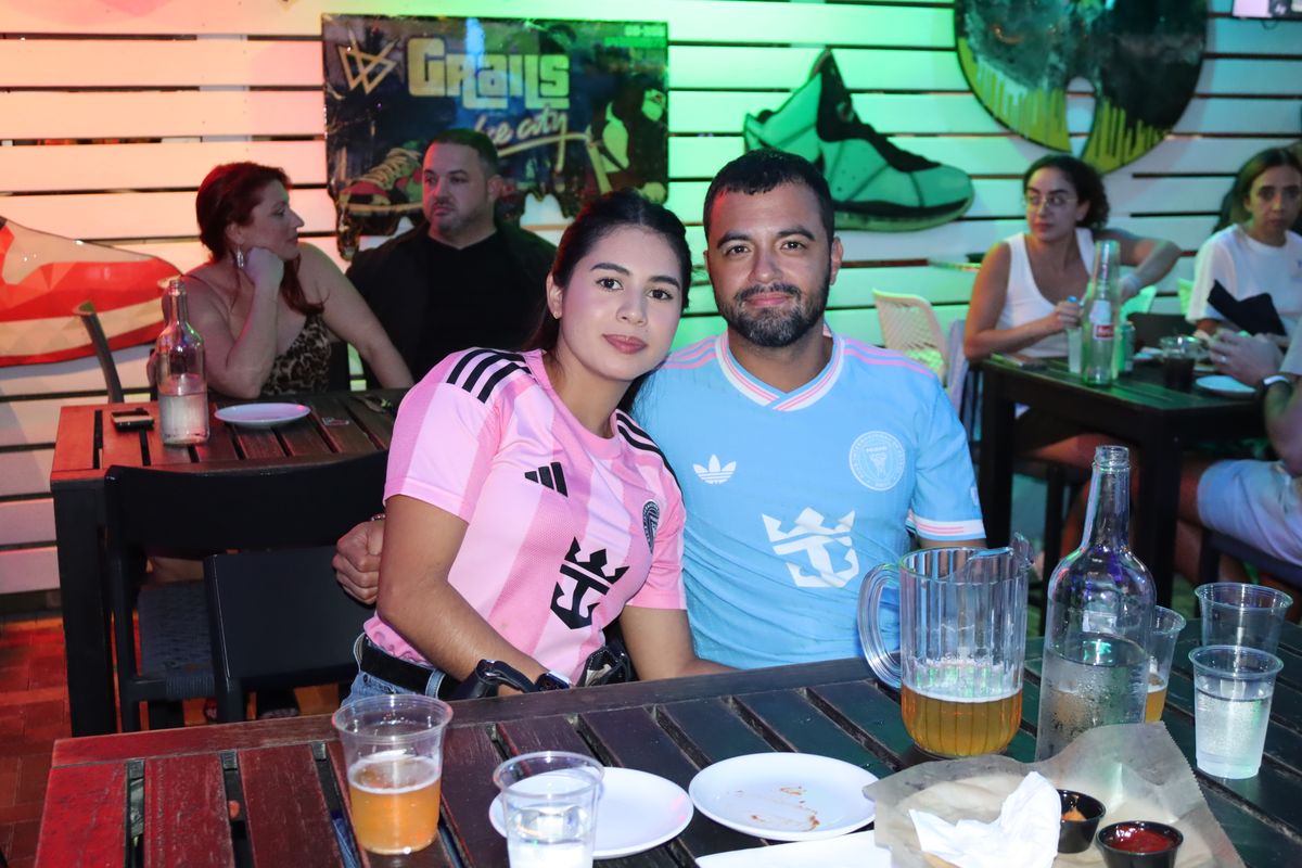 Couple in matching Inter Miami CF jerseys at a Grails Miami table on an Inter Miami match night