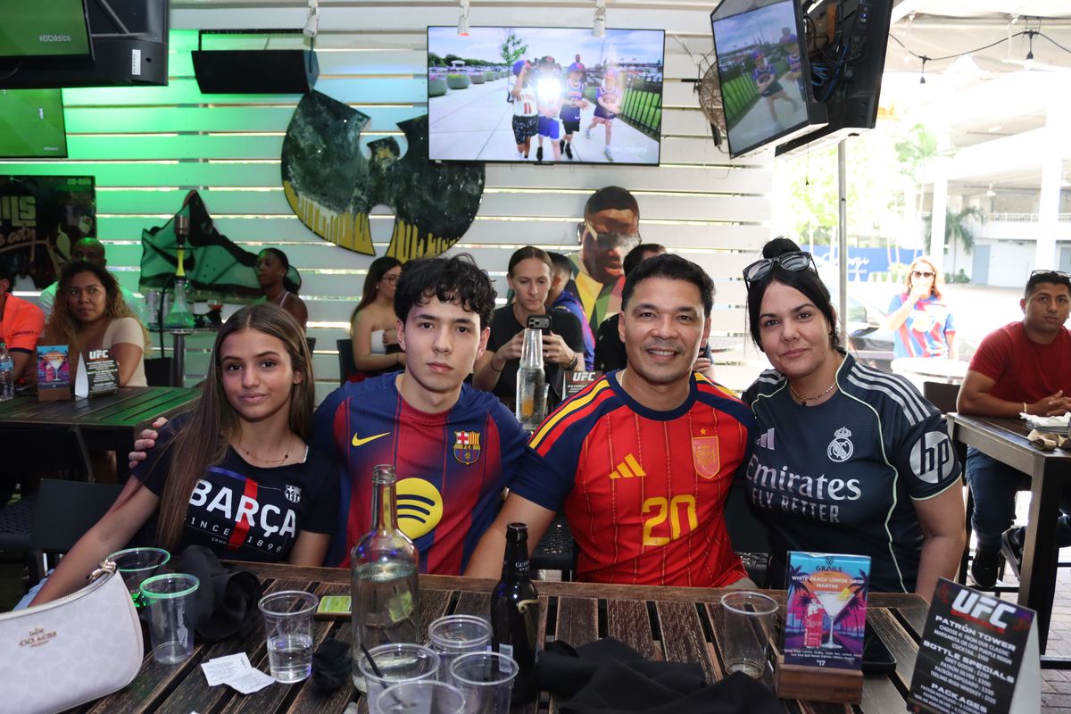 Family of four in rival Barcelona and Real Madrid jerseys at a patio table during an El Clásico watch party at Grails Miami