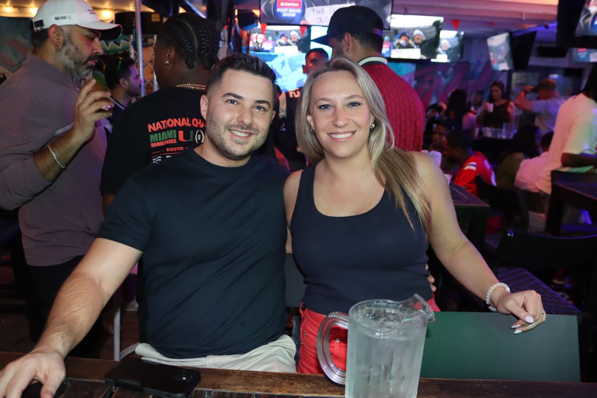 Couple at the Grails Miami bar with a Miami Hurricanes National Championship roster shirt during a College Football Playoff watch party