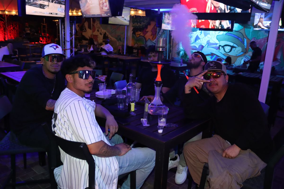 Group of friends around a hookah at a Grails Miami patio table — group hookah in Miami
