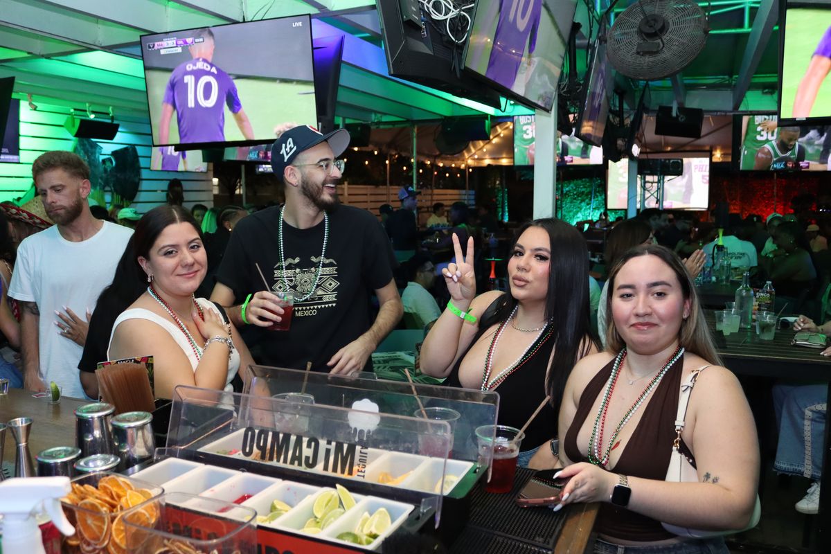 Group of friends in Mexico-themed bead necklaces at the bar during a Liga MX watch party at Grails Miami