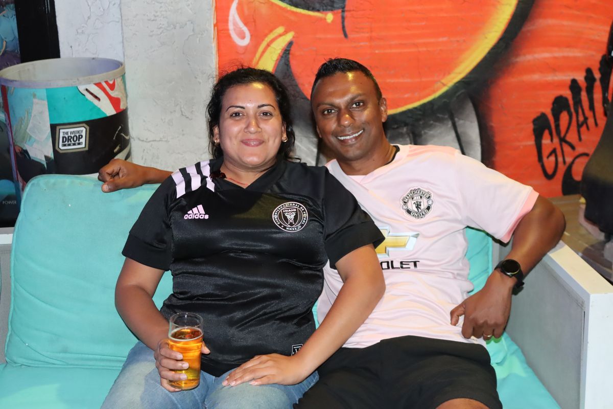 Couple wearing Inter Miami and Manchester United jerseys at the Grails Miami Premier League watch party in Miami