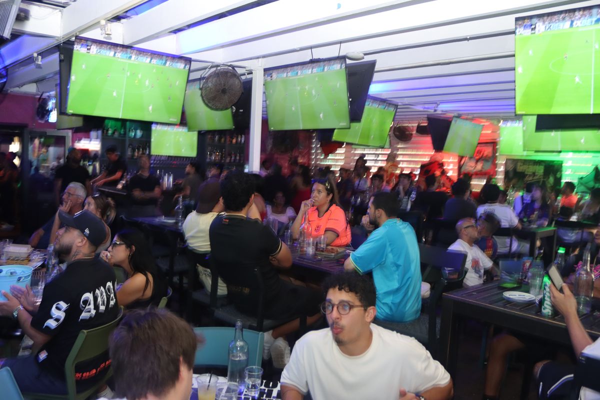 Crowd of soccer fans watching FC Barcelona on overhead TVs at a packed Grails Miami in Wynwood.