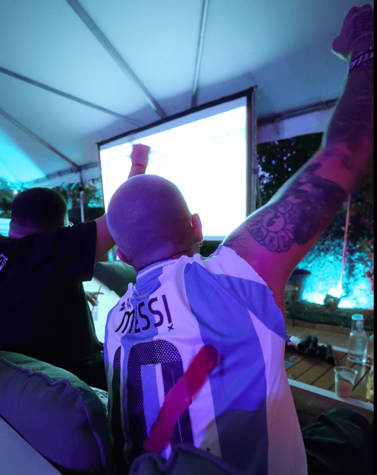 Fan in an Argentina Messi #10 jersey raising arms in celebration during a World Cup match at Grails Miami