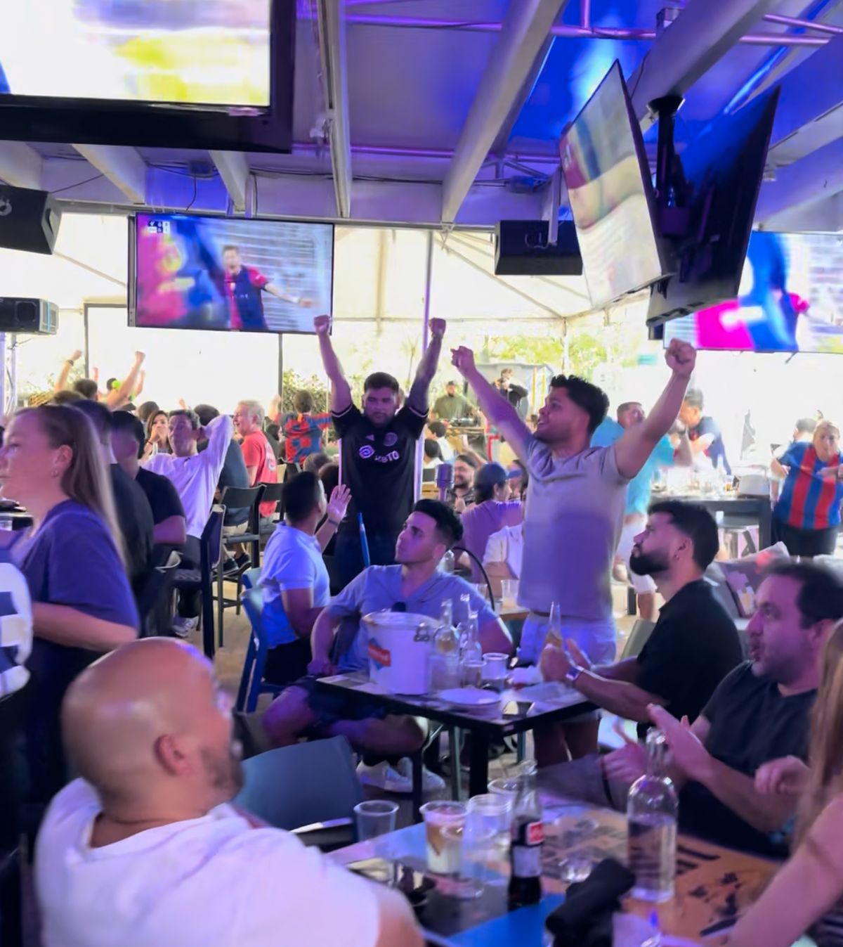 Two men with arms raised celebrating a Concacaf Gold Cup goal on the Grails Miami patio in Miami