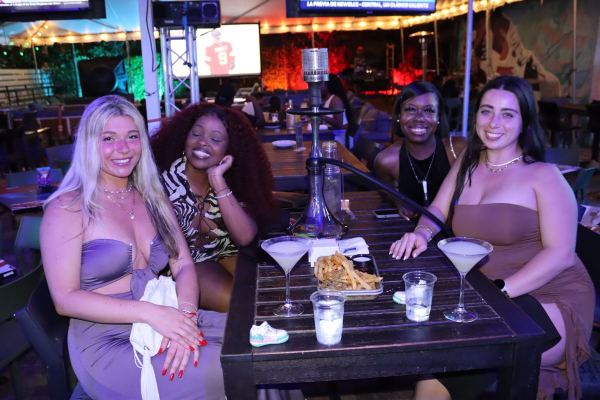 Four women posing together at the Grails Miami patio table with hookah and martini cocktails — girls-night hookah in Miami