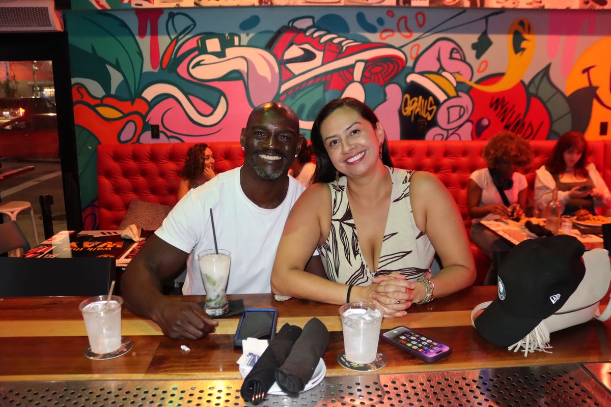 Couple on a date night in a mural-backed booth with cocktails at Grails Miami in Wynwood