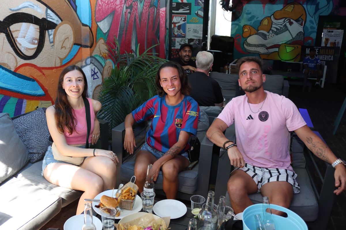 Three friends in Inter Miami soccer jerseys posing on the Grails Miami patio couch during a match