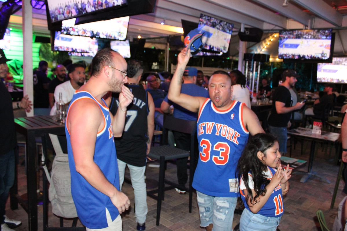 Knicks fans in New York #33 jerseys cheering with a child at Grails Miami during an NBA watch party