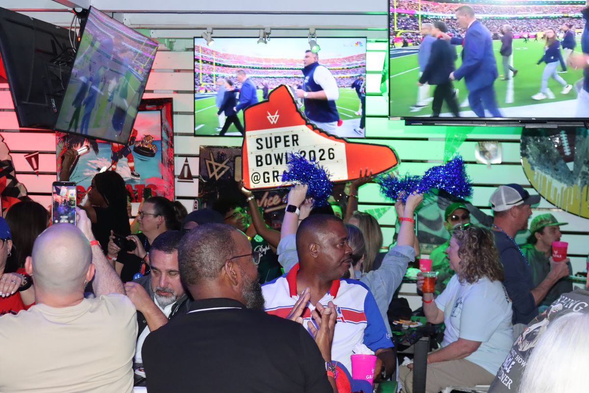 Crowd of fans at the Super Bowl 2026 watch party beneath illuminated screens at Grails Miami.