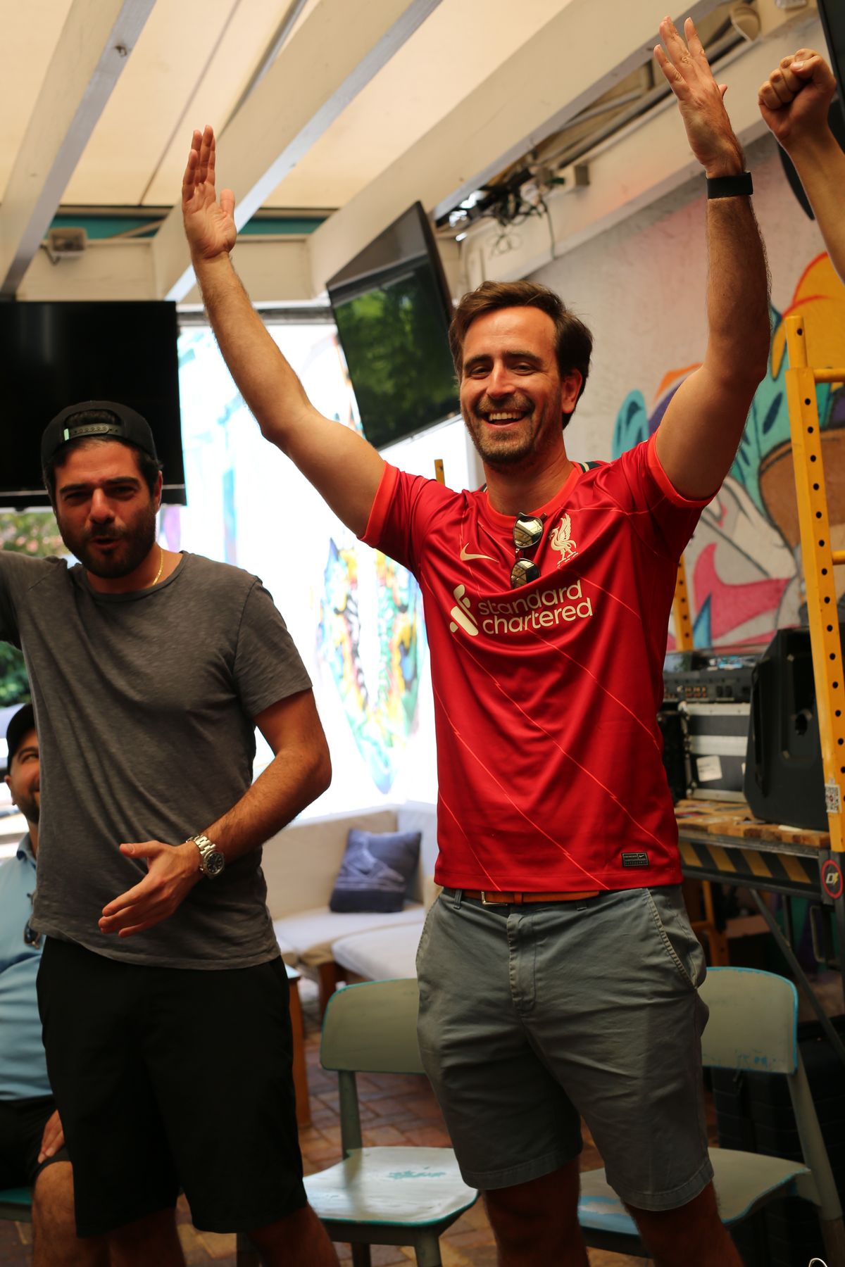 Liverpool FC fan with arms raised celebrating a goal during a Premier League match at Grails Miami in Wynwood