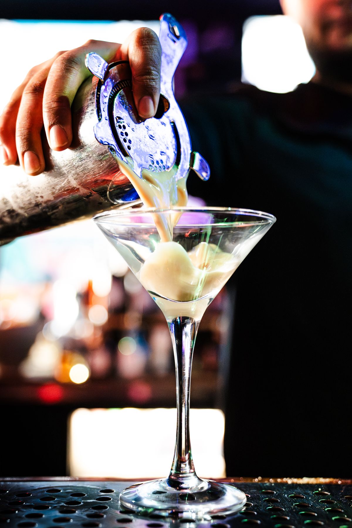 Bartender pouring a happy hour cocktail behind the bar at Grails Miami in Wynwood — Mon-Fri until 7 PM, $7 signature cocktails.