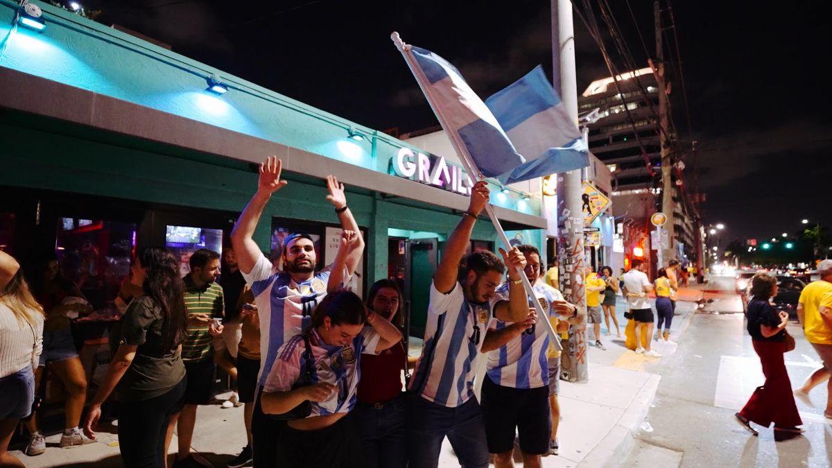 Argentina fans waving the national flag outside Grails Miami at night during a World Cup celebration