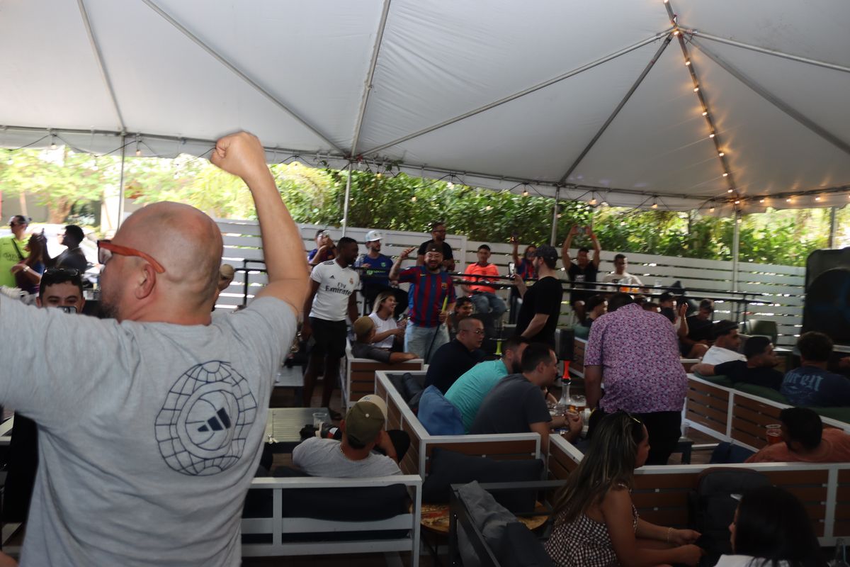 Premier League fan fist-pumping in celebration on the Grails Miami patio during a marquee weekend match