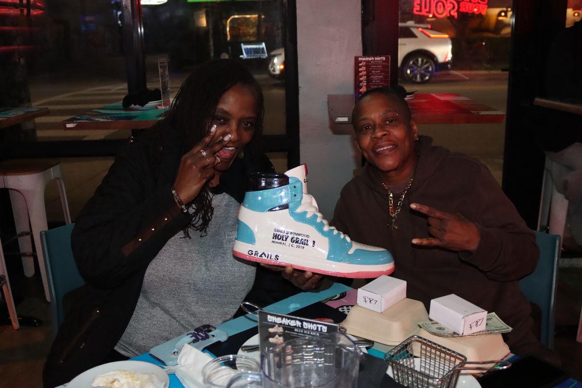 Two guests sharing the oversized Holy Grail shareable sneaker cocktail at Grails Miami