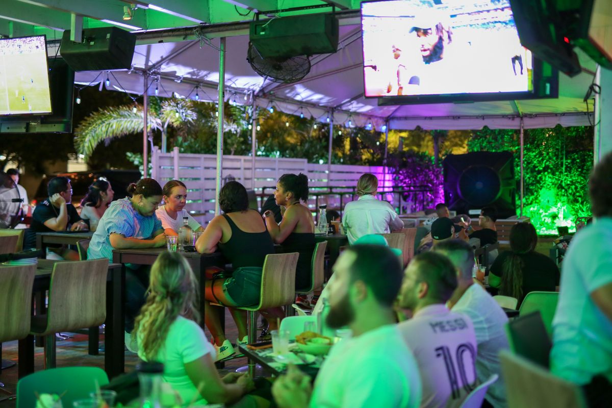 Man in a white Lionel Messi #10 jersey watching Inter Miami on the Grails Miami patio TVs