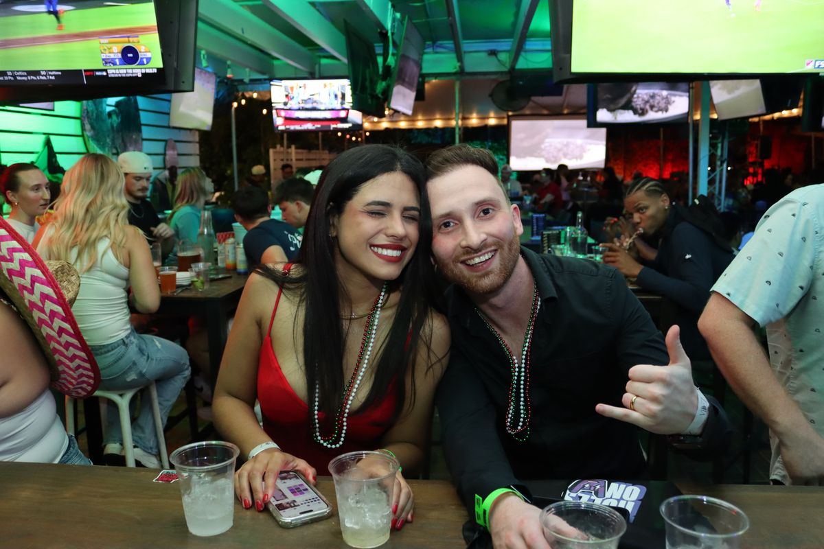 Couple posing together at a Grails Miami table in Mexico-colored beads on a Liga MX match night