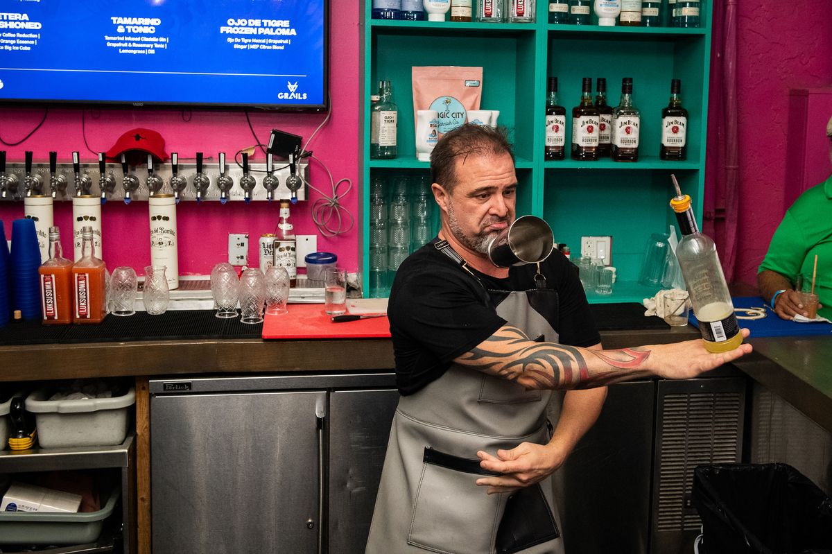 Flair bartender tossing a liquor bottle behind the happy hour bar at Grails Miami in Wynwood