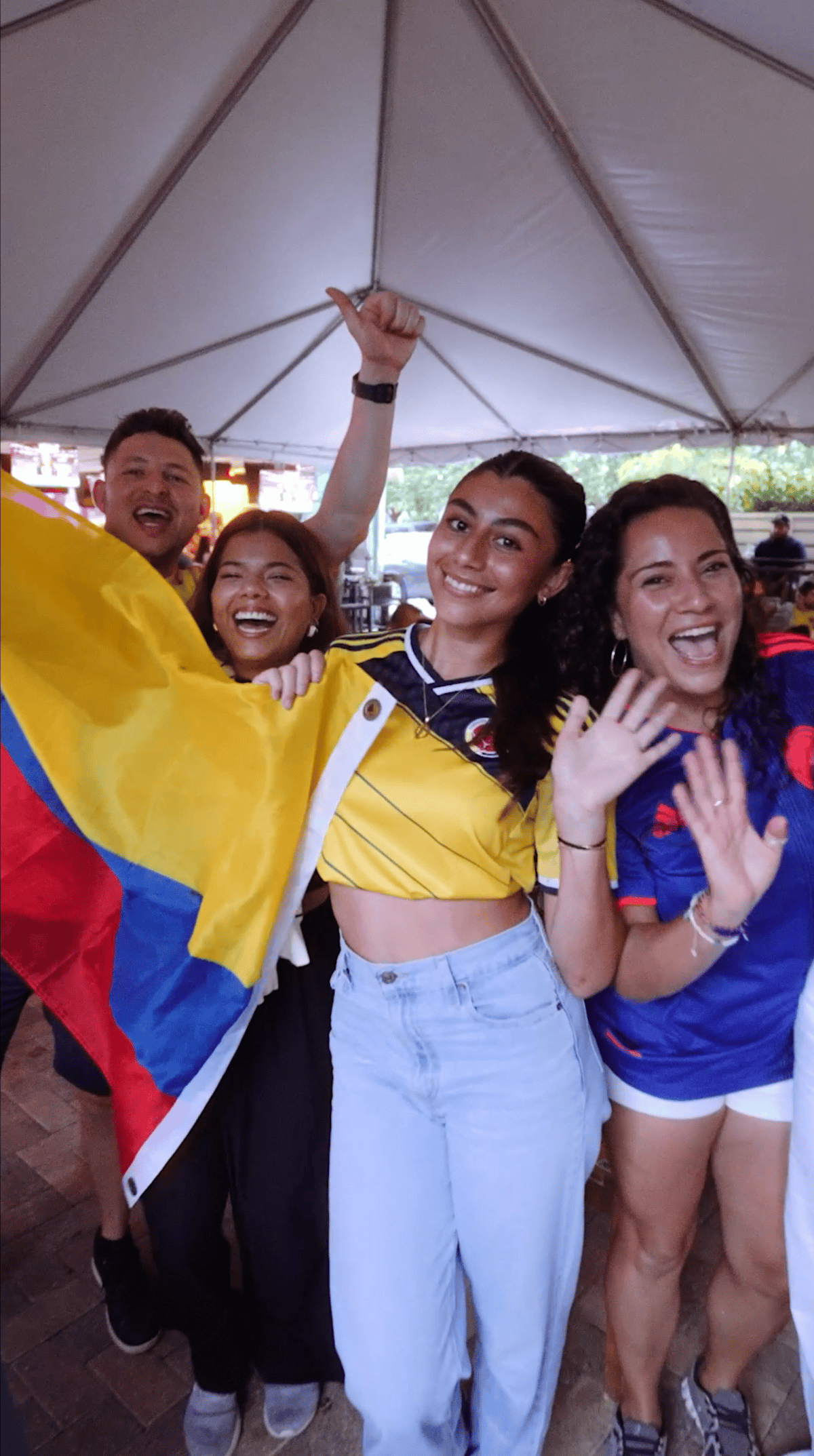 Colombia fans in yellow jerseys waving the national flag on the patio at Grails Miami, Miami's World Cup watch party bar
