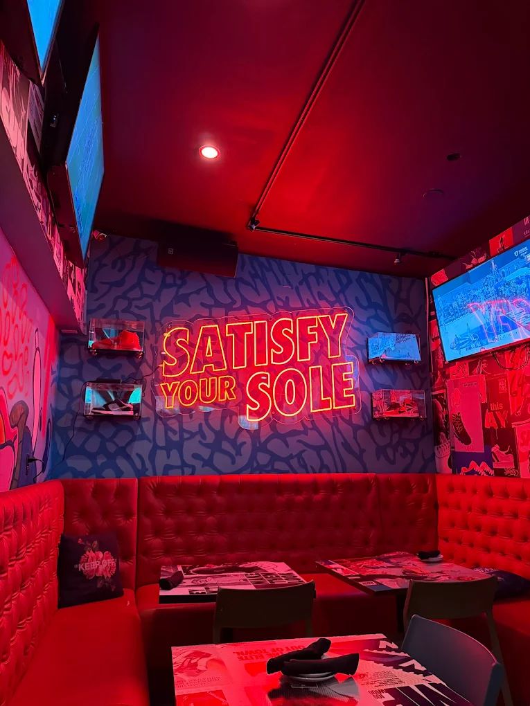 Satisfy Your Sole neon sign glowing on the Grails Miami lounge wall, the indoor seating for WNBA watch parties