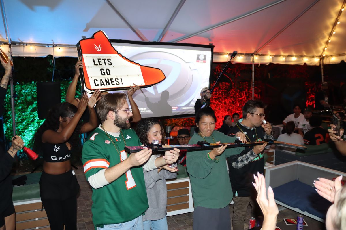 Miami Hurricanes fans gathered around a Hurricanes shot-ski during a College Football Playoff watch party at Grails Miami
