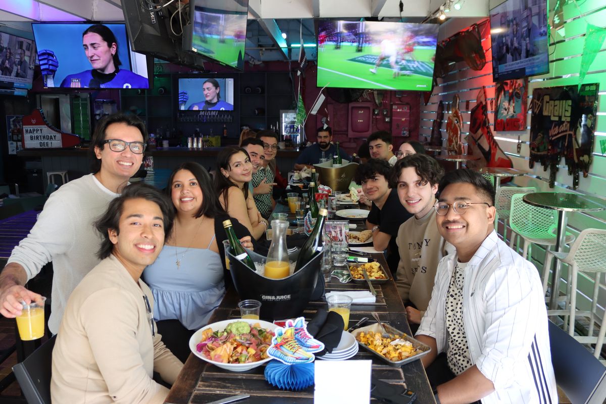 Large group of friends around a Wynwood brunch table with Grails-branded mimosa bottles.