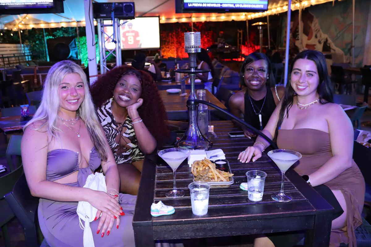 Four women sharing a hookah and cocktails on the covered Miami Vice Patio at Grails Miami