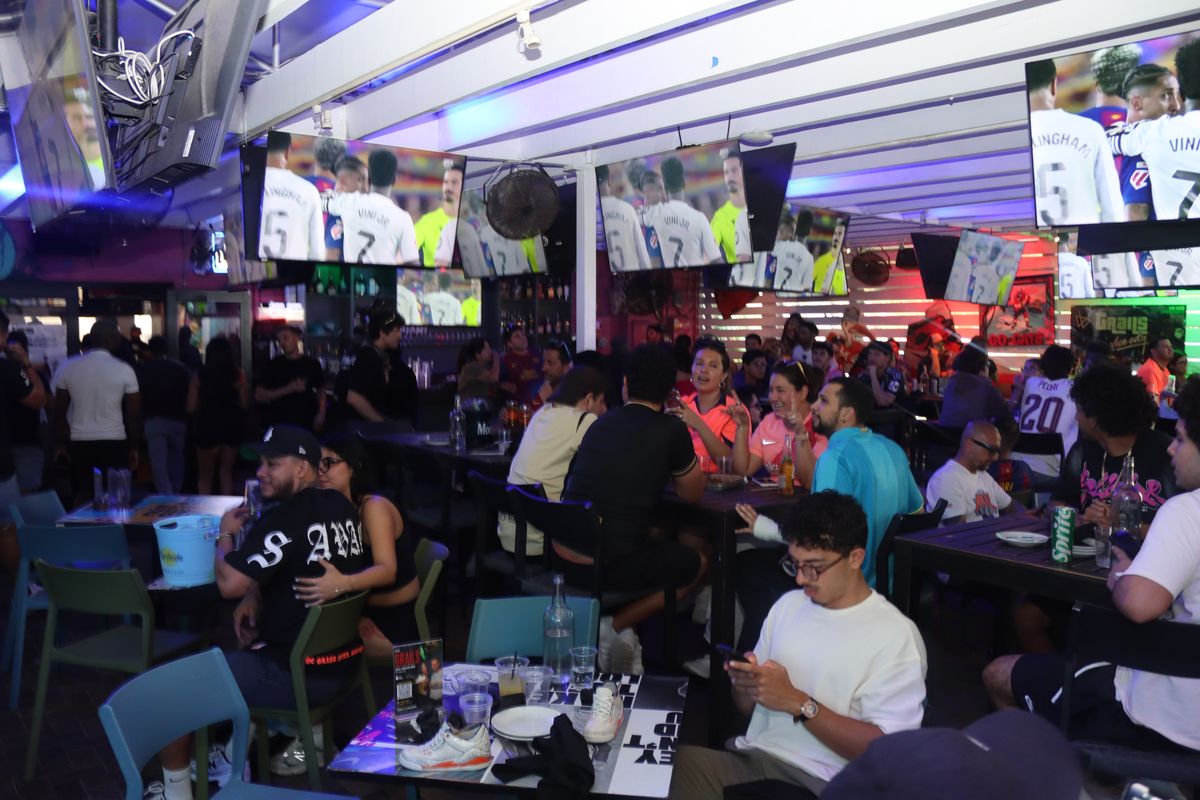 Packed indoor bar with overhead TVs showing a Champions League match at Grails Miami, Miami's home UCL watch party bar