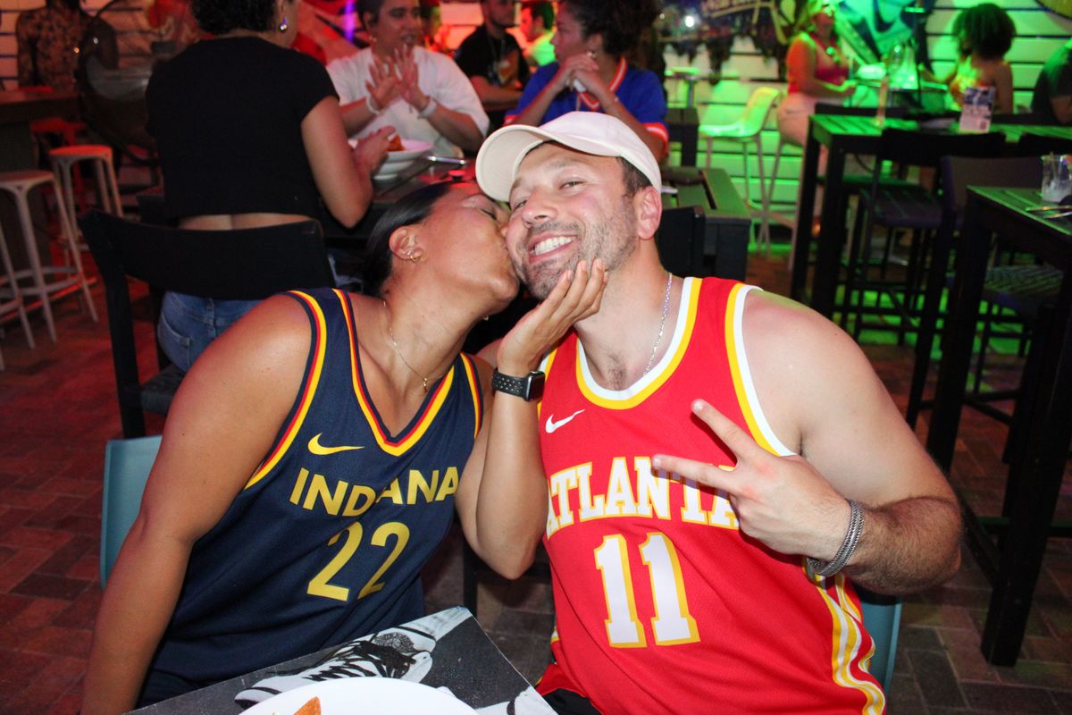 Couple in Indiana Fever and rival NBA team jerseys cheering at Grails Miami during a WNBA watch party, Miami's WNBA bar