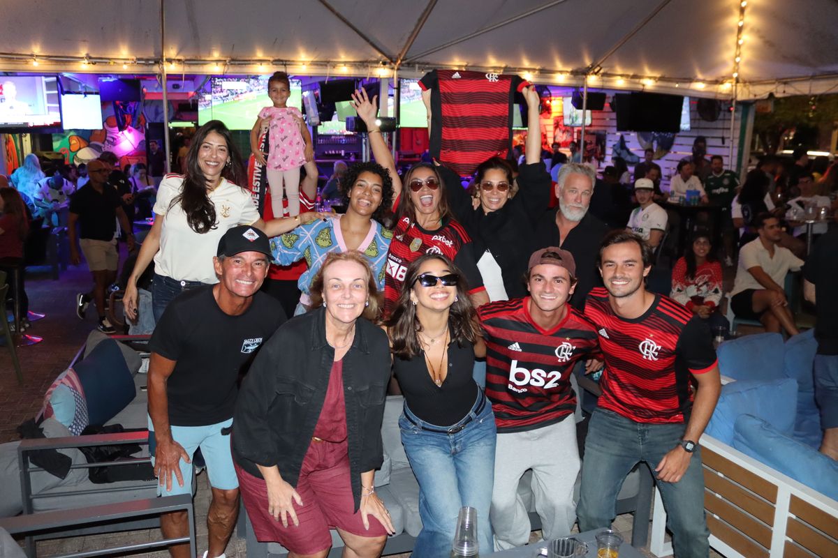 Group of Flamengo fans in red-and-black jerseys holding a CR Flamengo jersey overhead at the Grails Miami Copa Libertadores watch party in Miami