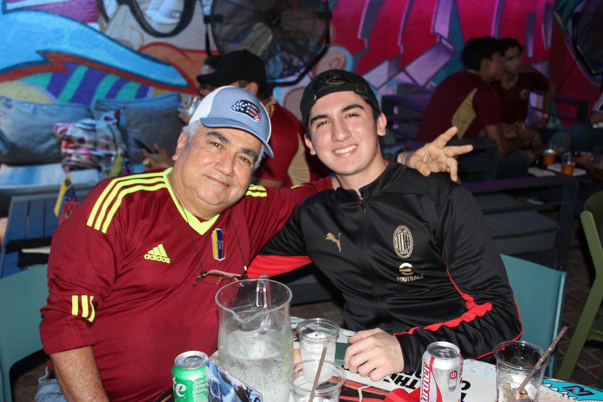 AC Milan fan in a Rossoneri jacket posing at a Grails Miami patio table during a Serie A watch party