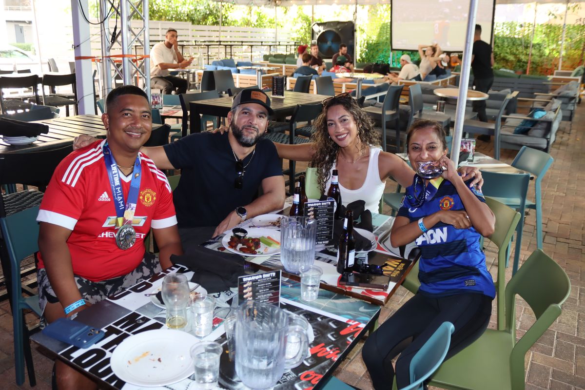 Group of Manchester United fans in red jerseys watching a UEFA Europa League match on the Grails Miami patio in Miami