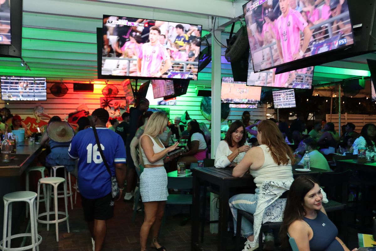 Crowded Grails Miami patio of fans watching an Inter Miami CF match on multiple overhead TVs