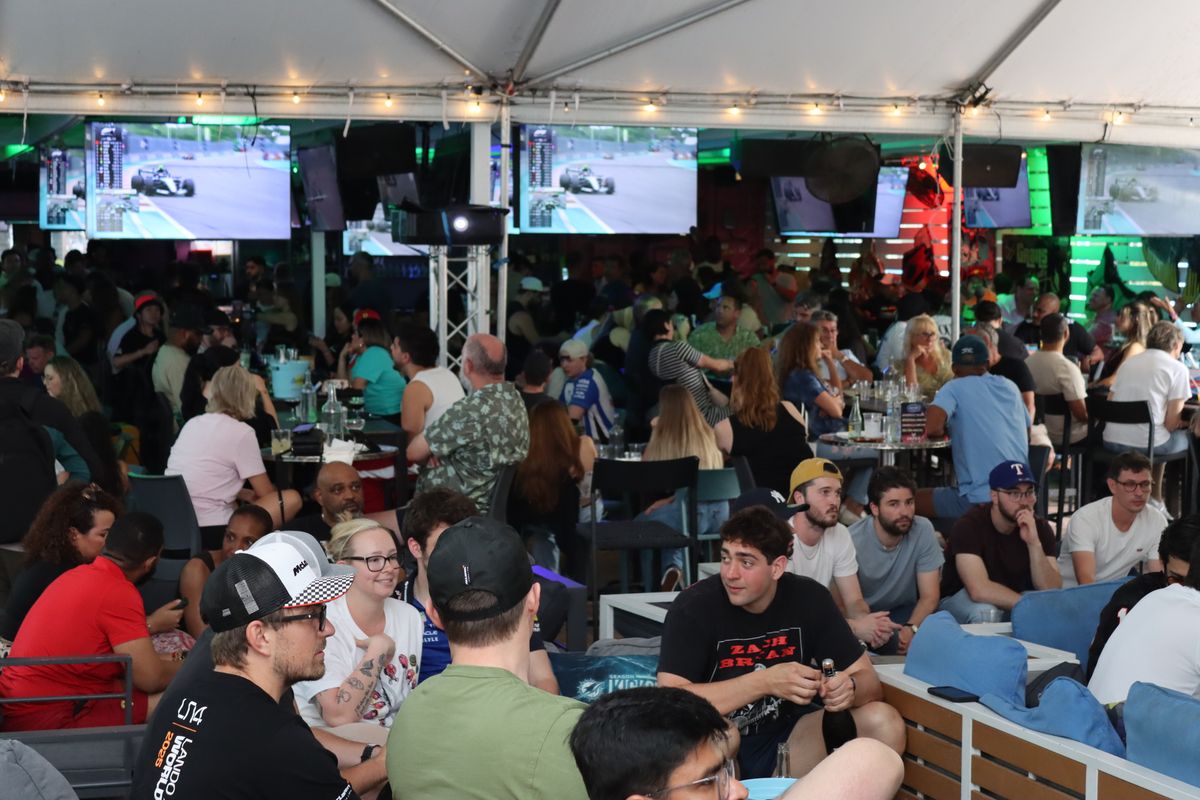 Crowd of fans watching the Formula 1 Miami Grand Prix on overhead TVs at a packed Grails Miami.