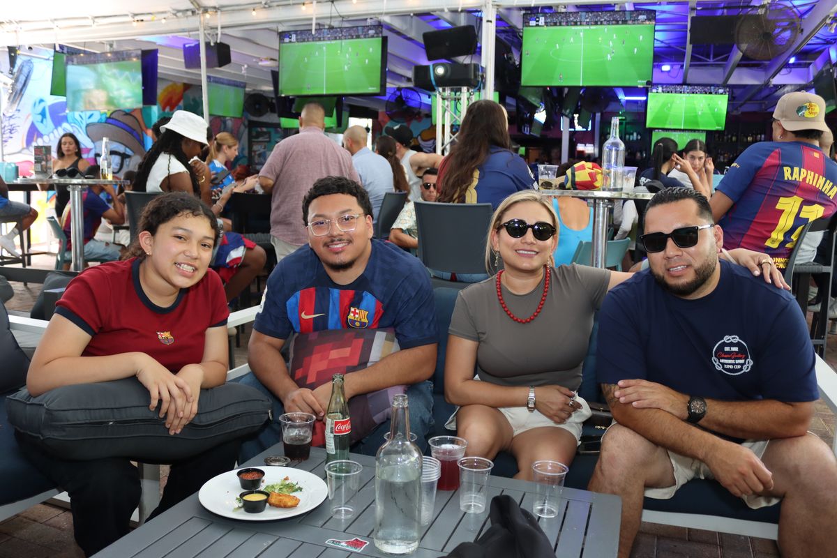 Family of four watching a Champions League match together on the Grails Miami patio banquette