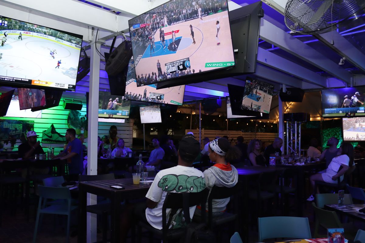 Couple watching basketball on the Grails Miami patio during a WNBA Playoffs night
