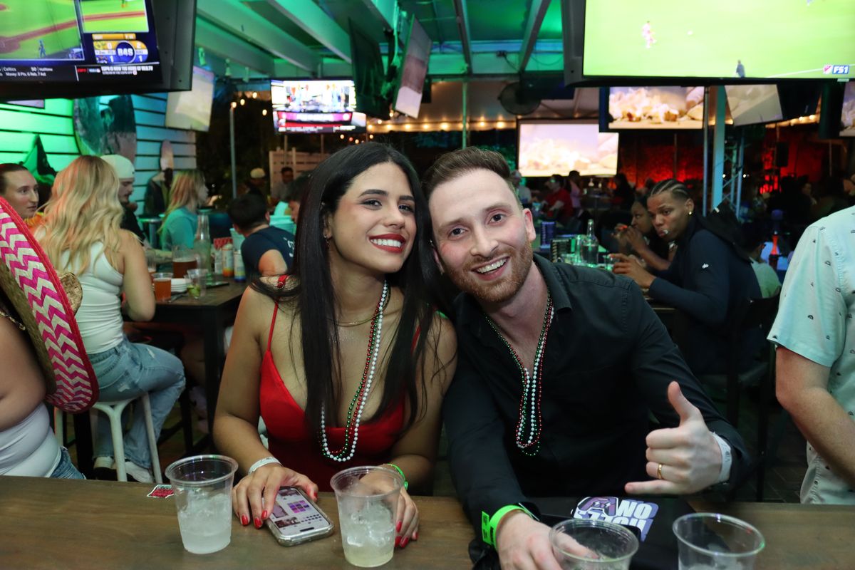 Couple posing together at a Grails Wynwood table in Mexico-colored beads on a Liga MX match night