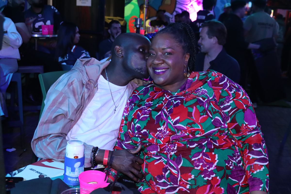 Smiling couple sharing a moment at their table during a packed NFL watch party at Grails Miami in Wynwood