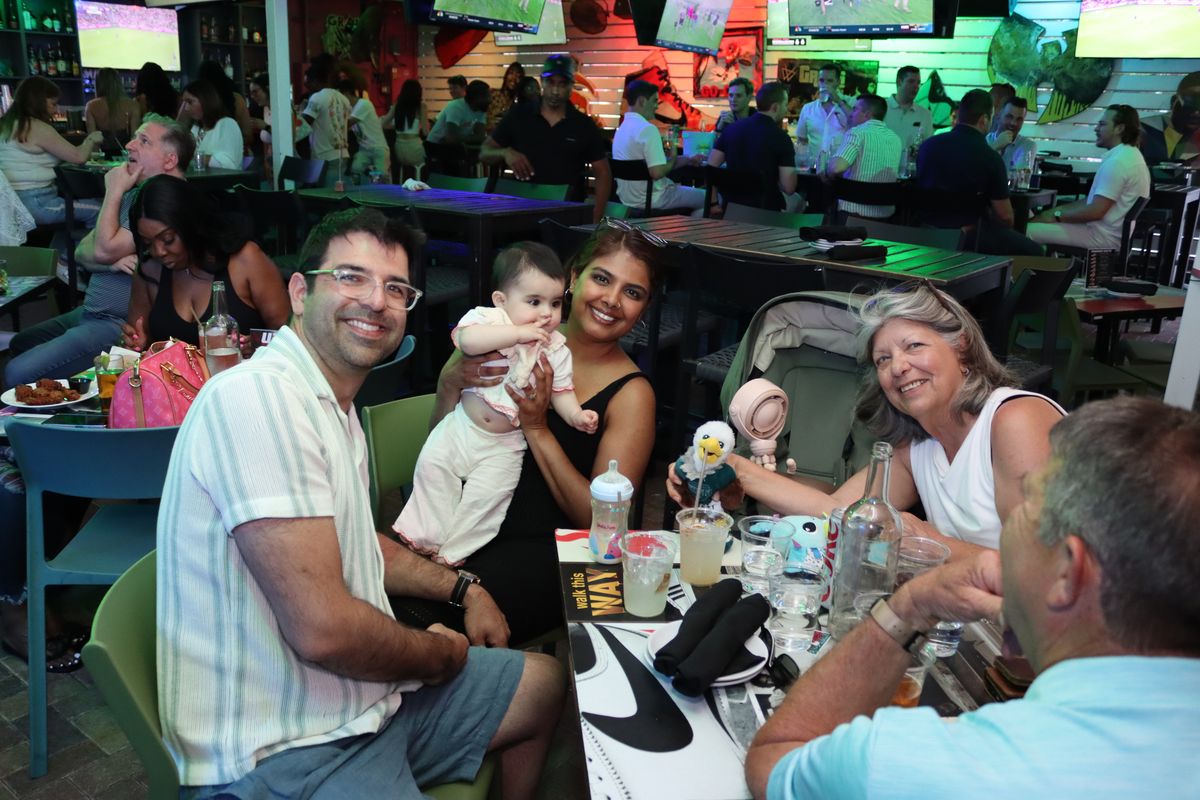 Family with a baby seated at a table during a game at Grails Miami, a family-friendly sports bar near Edgewater in Wynwood